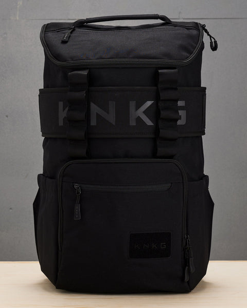 Large black CORE Backpack sitting on wooden box with matching weight lifting belt attached to backpack sleeve