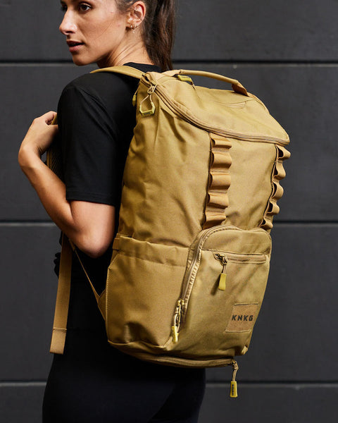Woman wearing desert KNKG CORE Backpack inside gym