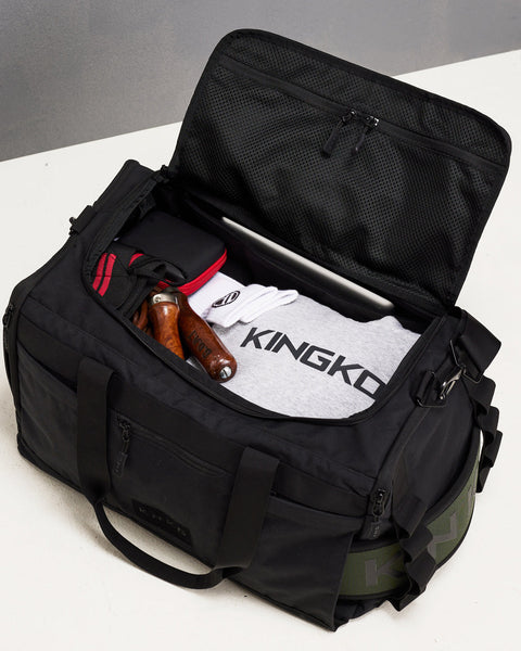 Birds eye view of black CORE Duffel packed with KINGKONG hoodie, KNKG green lifting belt, skipping rope, iPad and workout accessories