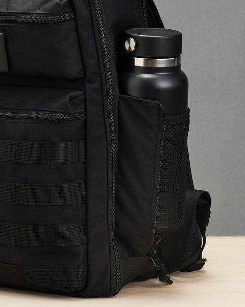 Close up of mesh side pocket of Small black KNKG CONQUER Backpack with drink bottle packed inside