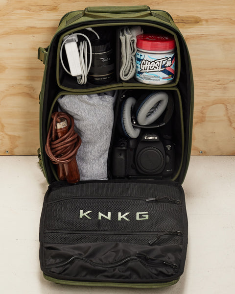 Internal view of small green KNKG CONQUER Backpack dividers packed with camera and gym gear