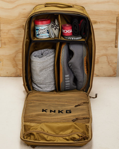 Internal dividers of desert KNKG CONQUER Backpack packed with shoes, GHOST pre-workout, ROGUE resistance bands and other workout accessories