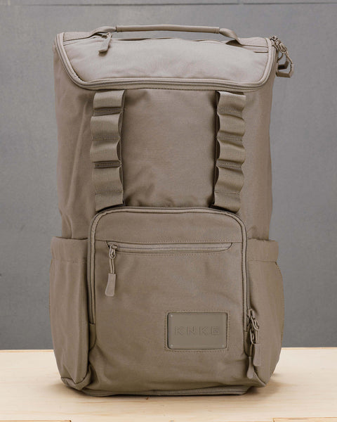 Front view of beige neutral CORE Backpack sitting on wooden box