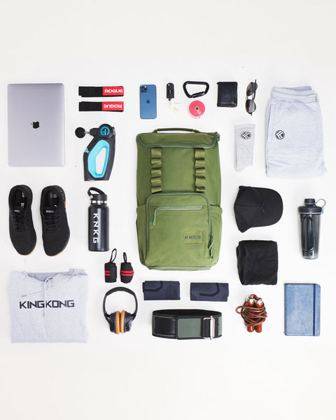 Flat lay of workout gear that fits inside of large green CORE Backpack