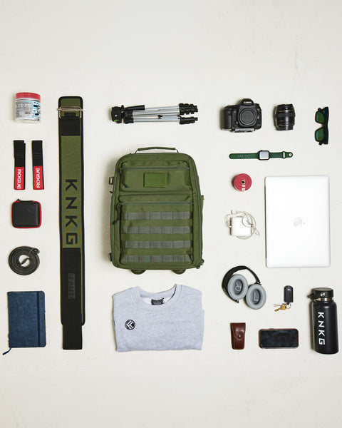 Flat lay of gym gear that fits inside of small green KNKG CONQUER Backpack