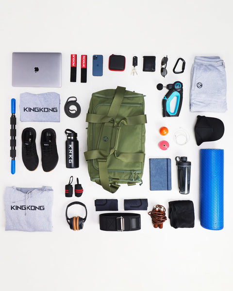 Flat lay of large green CORE Duffel surrounded by gym gear that fits inside duffel bag