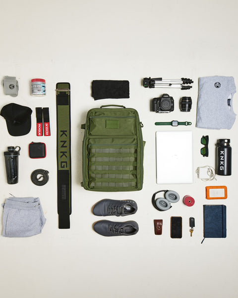 Flat lay of gym gear that fits inside large green CONQUER Backpack
