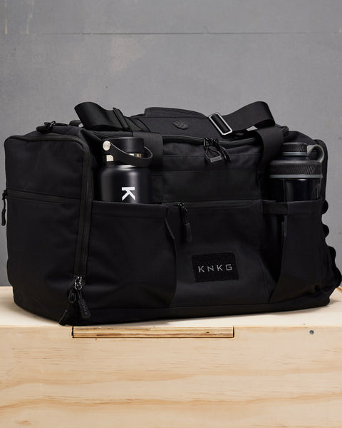 Drink bottle and shaker packed inside large black KNKG CORE Duffel bottle pockets