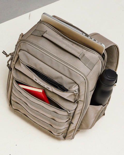 Pockets of neutral beige KNKG CONQUER backpack packed with laptop, bottles and notebook