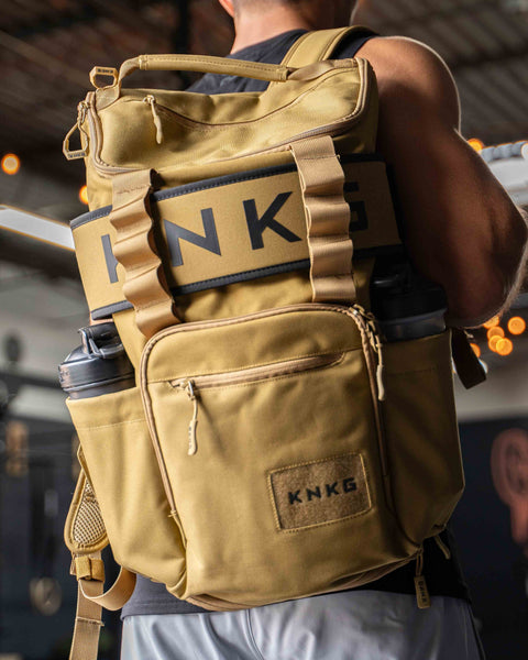 Man wearing large desert CORE Backpack over shoulder inside gym