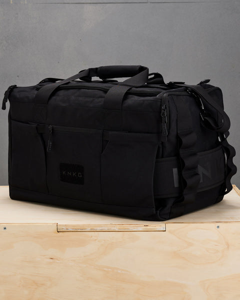 Side view of large black KNKG CORE Duffel with matching black lifting belt packed in sleeve