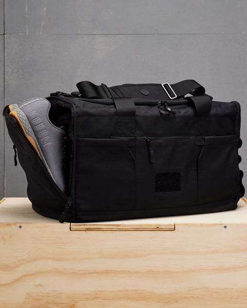 NOBULL sneakers packed inside large black KNKG CORE Duffel wet zone / shoe compartment