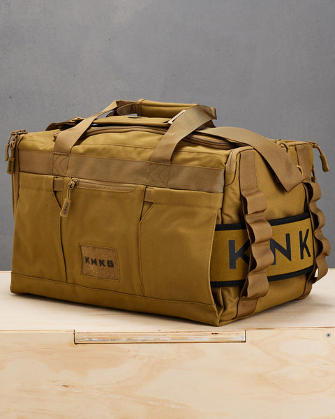 Desert CORE Duffel with matching lifting belt sitting on wooden box
