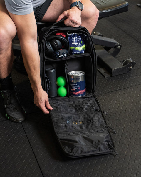 Small black KNKG CONQUER Backpack internal dividers packed with protein powder, headphones and gym essentials