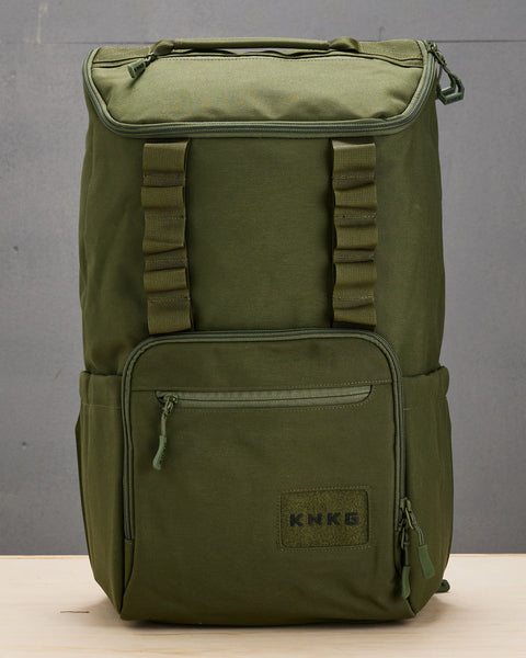 Front view of large green CORE Backpack sitting on wooden box