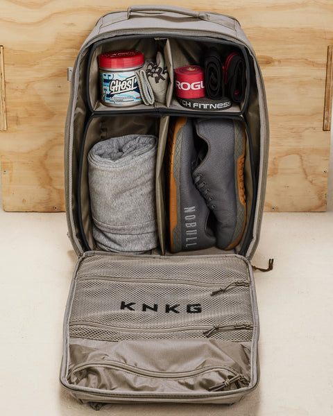 Internal dividers of beige neutral large KNKG CONQUER Backpack neatly organized and packed with shoes, clothes, GHOST pre-workout, ROGUE accessories and wrist wraps
