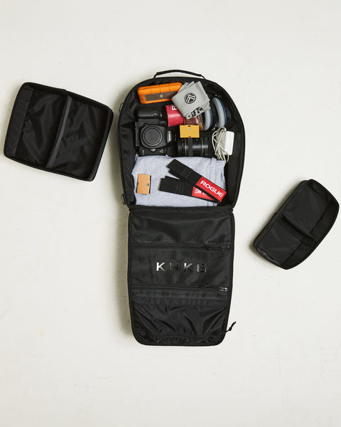 Birds eye view of Small black KNKG CONQUER Backpack packed with camera and gym gear