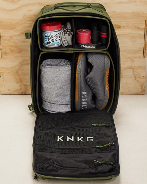 Internal dividers of  large green CONQUER Backpack neatly packed and organized with shoes, hoodie, GHOST pre-workout, wrist wraps and other fitness accessories