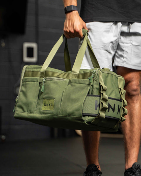 Man holding green CORE Duffel in fist