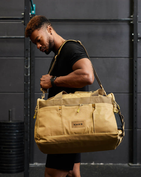 Man in gym wearing large desert CORE Duffel over shoulder
