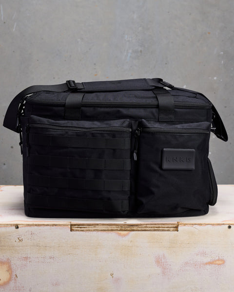 Front view of black CONQUER Duffel sitting on wooden box