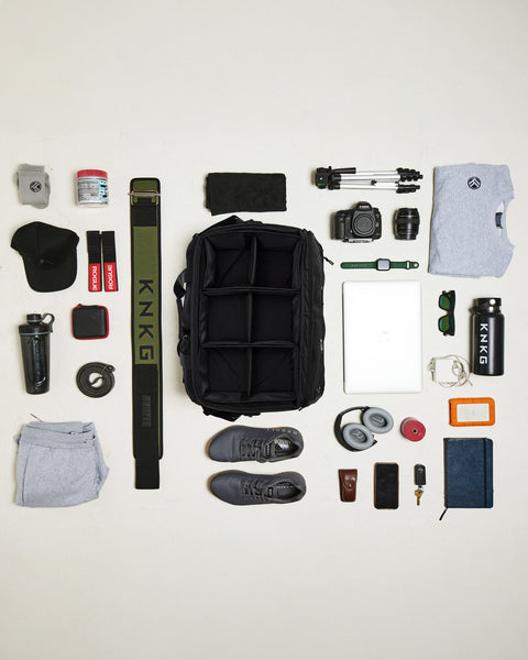 Birds eye view of gym gear being packed inside of black CONQUER Duffel