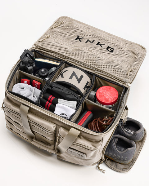 Birds eye view of neutral beige KNKG CONQUER Duffel with internal organized dividers packed with gym essentials