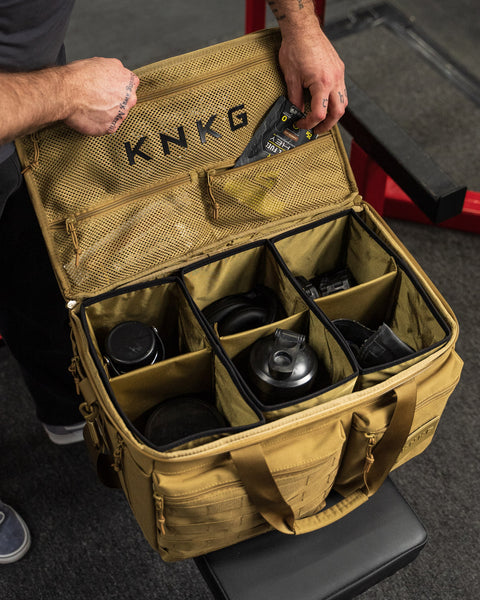 Man packing gym gear inside of desert CONQUER Duffel internal dividers