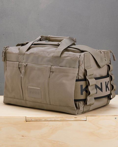 Side view of beige neutral CORE Duffel with weight lifting belt attached inside sleeve