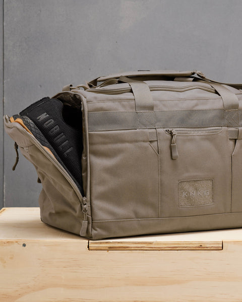 Sneakers packed inside side shoe compartment of beige neutral CORE Duffel