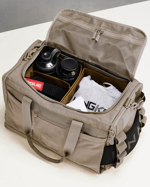 Beige neutral CORE Duffel Internal divider organization system packed with drink bottles, wrist wraps and workout gear
