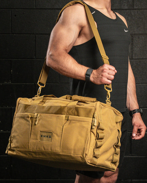 Man wearing large desert CORE Duffel over shoulder