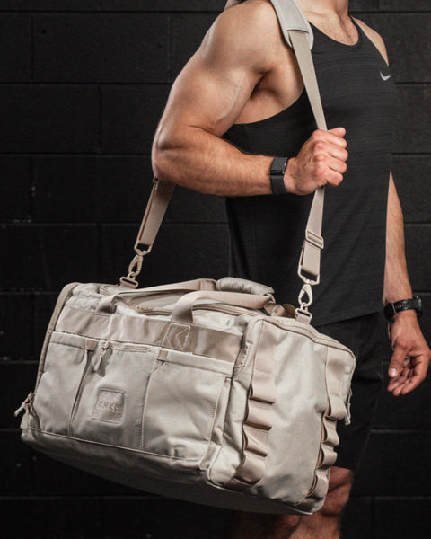 Man wearing large neutral beige CORE Duffel in gym