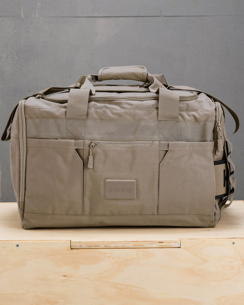 Front view of large neutral beige CORE Duffel sitting on wooden box