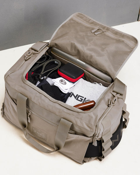 Birds eye view of large neutral beige CORE Duffel fully packed with workout gear, laptop, skipping rope and workout accessories