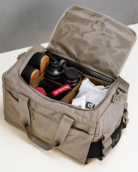 Birds eye view of internal divider system inside large neutral beige CORE Duffel, packed with shoes, bottles, workout clothes and fitness accessories