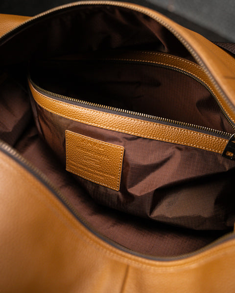Close up of brass zipper pocket inside large tan HERITAGE leather duffel