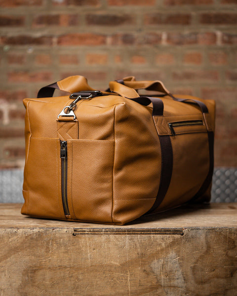 Side view showing large tan HERITAGE leather duffel bottle pocket