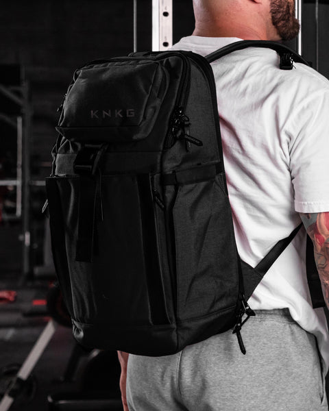 Black KNKG PLUS Backpack worn by man inside gym
