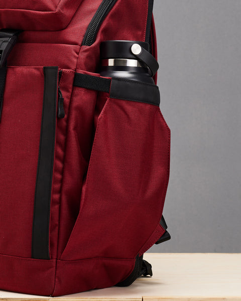 Close up of drink bottle inside side pocket of Red KNKG PLUS Backpack