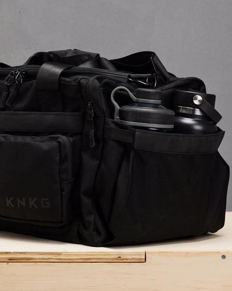Blender shaker and water bottle inside small black KNKG PLUS Duffel bag pockets