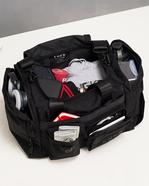 Birds eye view of small black KNKG PLUS Duffel bag packed with gym gear