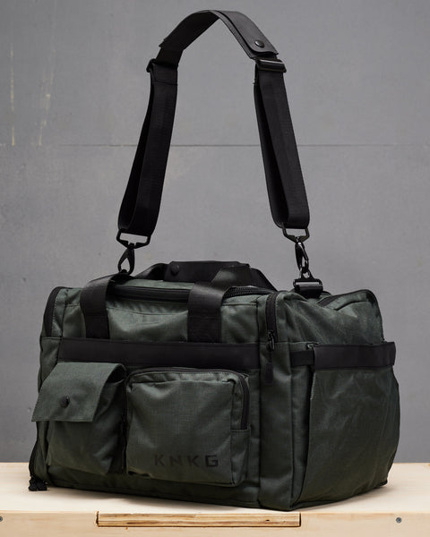 charcoal grey KNKG PLUS duffel bag sitting on wooden box