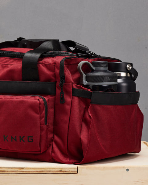 Drink bottle and shaker packed inside small red KNKG PLUS Duffel  pocket
