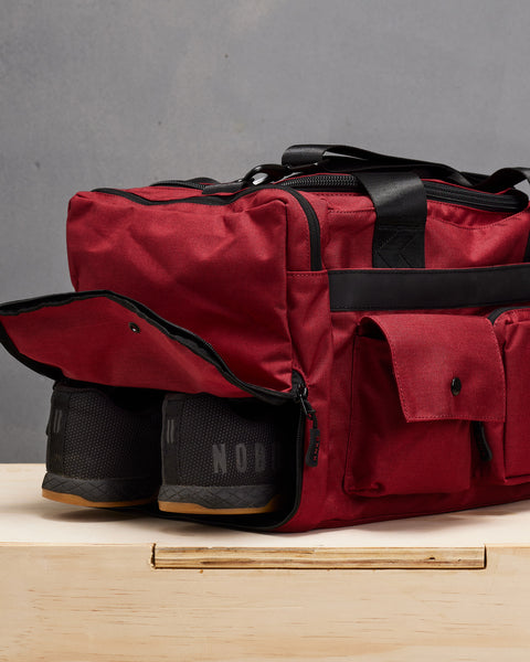 NOBULL sneakers inside small red KNKG PLUS Duffel  shoe compartment