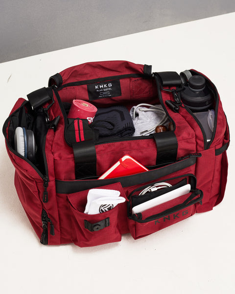 small red KNKG PLUS Duffel pockets and compartments fully packed with gym gear