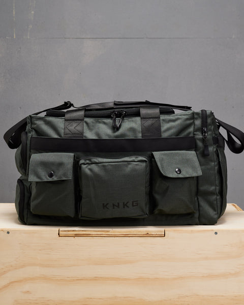 Front view of charcoal grey KNKG PLUS Duffel bag sitting on wooden box