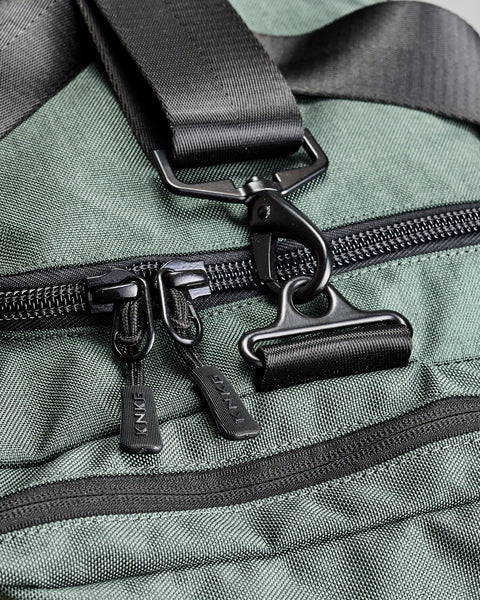 Close up of KNKG branded zippers and steel buckles on charcoal grey PLUS Duffel