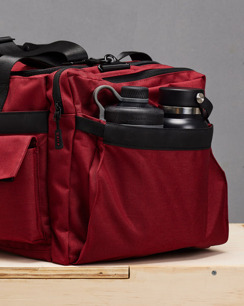 Side pocket of red PLUS duffel with 2 drink bottles