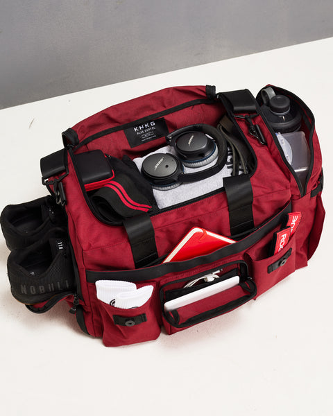 Birds eye view of red PLUS duffel packed with gym essentials
